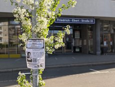 Gedenkplakat mit Straßenschild im Hintergrund
